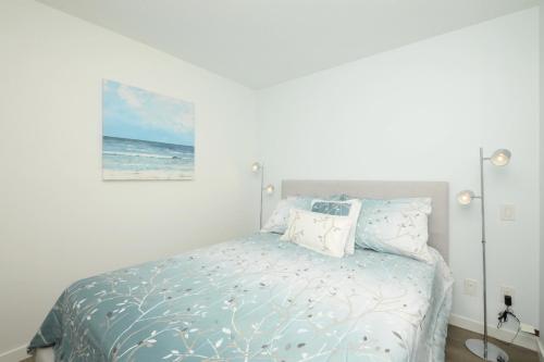 a bedroom with a bed with a picture of the ocean at Gorgeous Old Town Condo with Patio and Parking! in Victoria