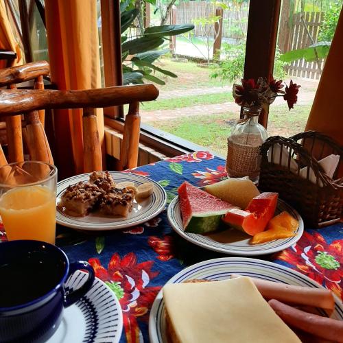 een tafel met borden vol eten en sinaasappelsap bij Pousada Raízes da Guarda in Guarda do Embaú