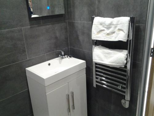 a bathroom with a sink and a mirror and towels at Lady Charlotte Guest rooms triple rooms in Dowlais