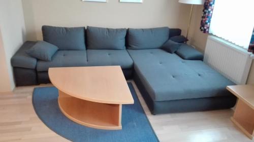 a living room with a blue couch and a table at Ferienhaus Lutzmannsburg mit direktem Thermenzugang und eigenem Garten in Lutzmannsburg