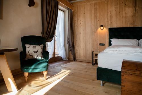 a bedroom with a bed and a chair and a window at Al Capriolo in Vodo Cadore