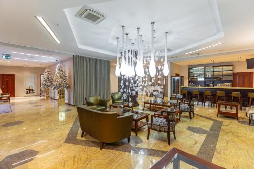 a hotel lobby with a chandelier and tables and chairs at Raikin Plaza Hotel in Moscow