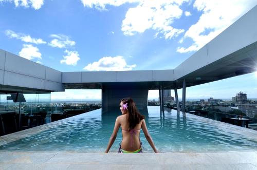 une femme dans une piscine sur le toit d'un bâtiment dans l'établissement Lex Hotel Cebu, à Cebu