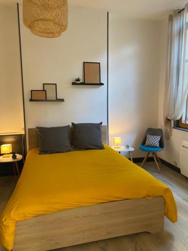 a bedroom with a yellow bed and two chairs at joli appartement quartier historique, 5 pers in Moulins