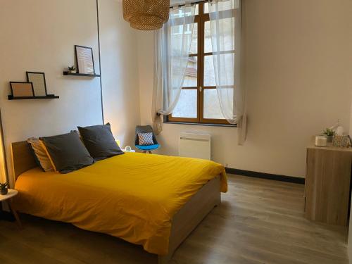 a bedroom with a bed with yellow sheets and a window at joli appartement quartier historique, 5 pers in Moulins