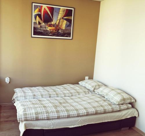 Bett in einem Zimmer mit einem Bild an der Wand in der Unterkunft Rise and Shine apartment in Juodkrantė