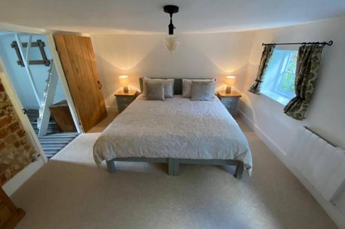 a bedroom with a bed with two lamps and a staircase at ROSE COTTAGE in Rowlands Castle