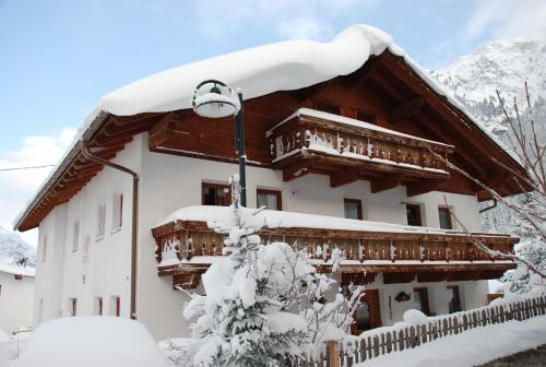 a building covered in snow with a light at Pension Steinkogel in Sankt Leonhard im Pitztal