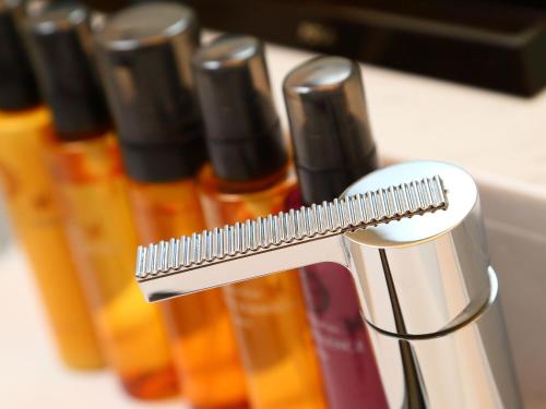 a silver toothbrush in front of bottles of liquid at Hotel Fine Garden Nara Horai in Nara