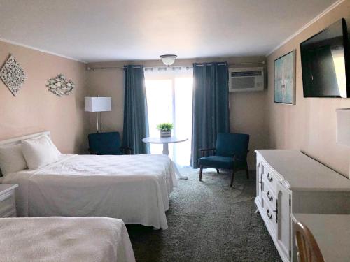 a hotel room with two beds and a table at Sands Of Time Motor Inn & Harbor House in Woods Hole