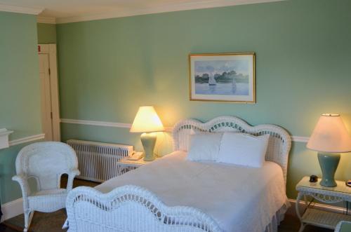 a bedroom with a bed with two chairs and two lamps at Sands Of Time Motor Inn & Harbor House in Woods Hole