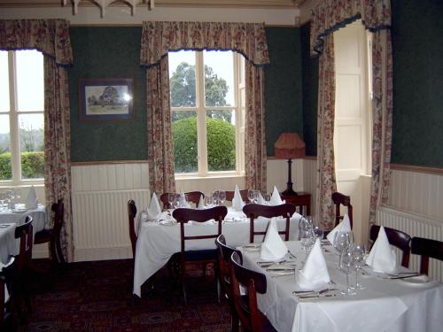 a dining room with white tables and chairs and windows at Richmond Country House & Restaurant in Cappoquin