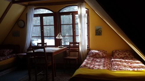 a bedroom with a bed and a desk and a window at Leśniczówka Jednorożec in Lipowo Kurkowskie