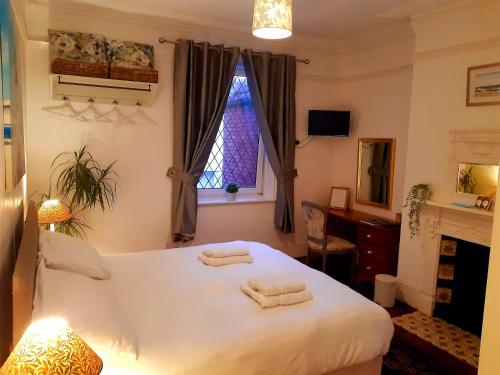 a bedroom with a white bed with two towels on it at Sandsides Guest House in Whitley Bay