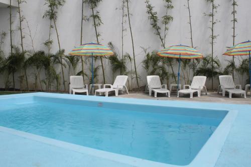 a group of chairs and umbrellas next to a pool at BB INN in Nuevo Vallarta