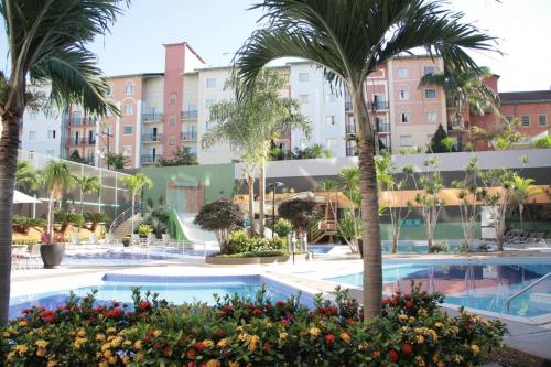 a resort pool with palm trees and buildings at Park Veredas Apart in Rio Quente