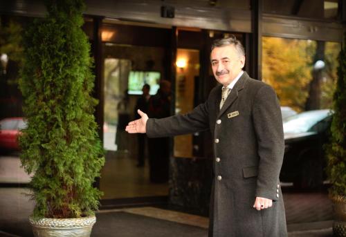 a man in a suit standing next to a tree at Premier Hotel Dnister in Lviv