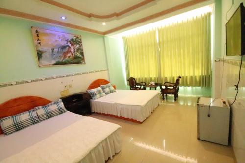 1 dormitorio con 2 camas, mesa y ventana en Rang Dong Hotel, en Mỹ Tho