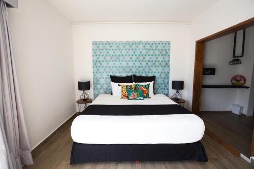 a bedroom with a large white bed and a blue wall at Casa Chukum - Hotel Boutique in Bacalar