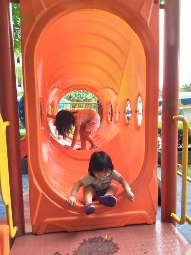 two children playing in an orange tunnel on a playground at Altiz Apartment Bintaro Plaza Residence in Tangerang