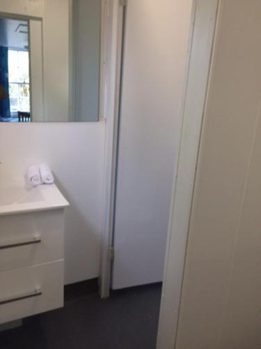 Baño blanco con lavabo y espejo en Tui Glen, en Raurimu