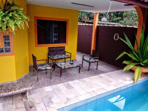 a patio with chairs and a swimming pool at Pousada Aconchego Bertioga in Bertioga