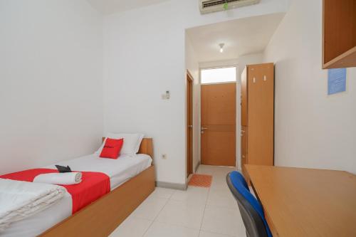 a hotel room with a bed and a desk and a room at RedDoorz Syariah Plus @ Wisma Bougenville Karawaci in Tangerang