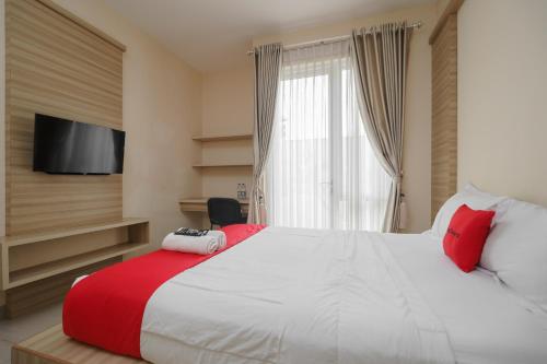 a bedroom with a large white bed with red pillows at RedDoorz Syariah Plus @ Wisma Bougenville Karawaci in Tangerang
