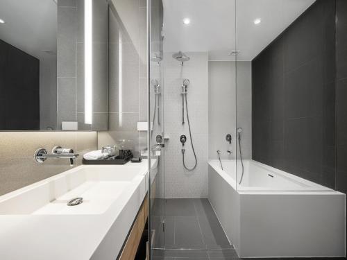 a bathroom with a tub and a sink and a shower at Oakwood Suites Bangkok in Bangkok