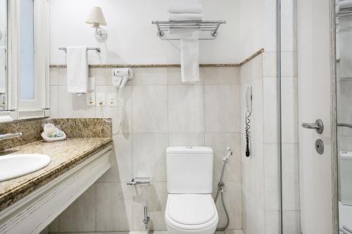 a white bathroom with a toilet and a sink at Apartamento com varanda no IL Campanário Resort in Florianópolis