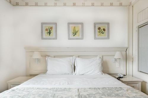 a bedroom with a white bed with three pictures on the wall at Apartamento com varanda no IL Campanário Resort in Florianópolis