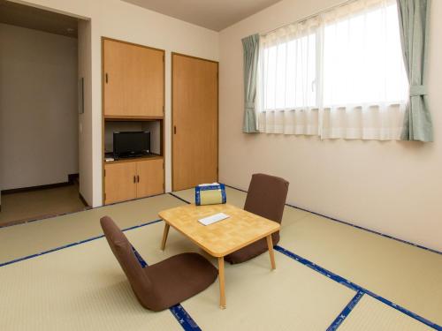 een kamer met een tafel en 2 stoelen bij Tabist Business Ryokan Duck Ishinomaki Hebita in Ishinomaki