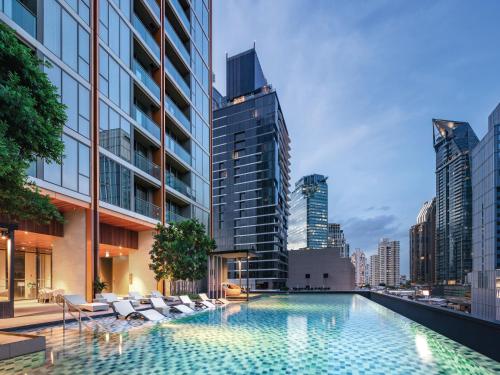 a swimming pool in the middle of a city with buildings at Oakwood Suites Bangkok in Bangkok