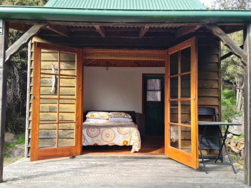 Cama en habitación pequeña con puertas de cristal en Manaaki Mai, Rustic Retreat Bush Cabin, en Christchurch