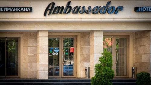 a building with a hotel sign on the side of it at Ambassador Hotel in Bishkek