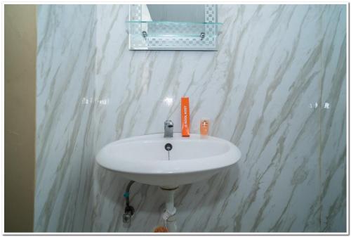 a white sink in a bathroom with a marble wall at KoolKost near Lokasari Square (Minimum Say 6 Nights) in Jakarta