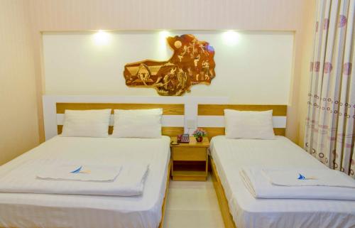 two beds in a hotel room with a horse head on the wall at Mui Tau Hotel Phan Ri Cua in Tuy Phong