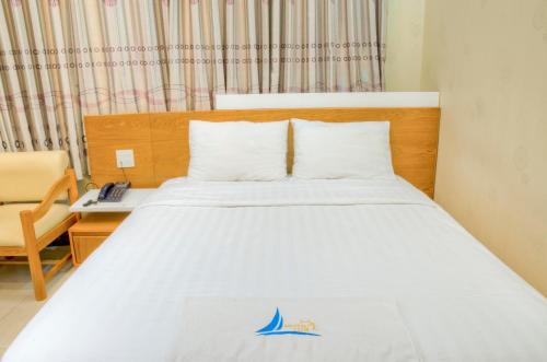 a bedroom with a large bed with a telephone and a chair at Mui Tau Hotel Phan Ri Cua in Tuy Phong