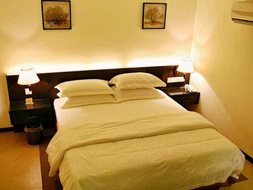 a bedroom with a large white bed with two lamps at ERNES Hotel in Perai