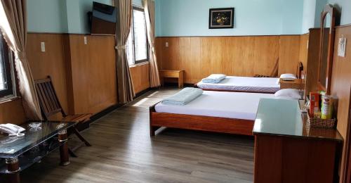 um quarto de hotel com duas camas e uma mesa em Cao Nguyen Hotel - Gia Lai em Pleiku