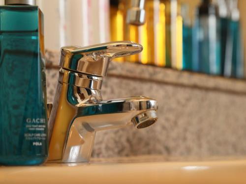 a bathroom sink with a faucet and a green bottle at Hotel Fine Garden Senboku in Sakai