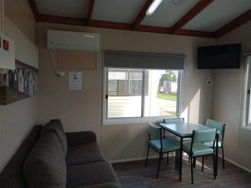 a room with a couch and a table and a window at Lang Lang Caravan Park 
