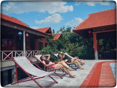 three women laying in lawn chairs on a porch at Trang An Village Homestay in Ninh Binh