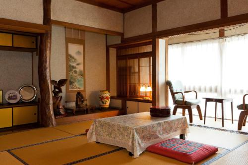 Habitación con sala de estar con mesa y ventana. en Hoshi Ryokan, en Tsuwano