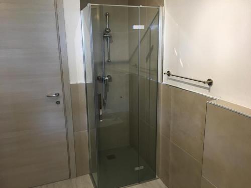 La salle de bains est pourvue d'une douche avec une porte en verre. dans l'établissement Laguna Palace Resort Apartment, à Aprilia Marittima