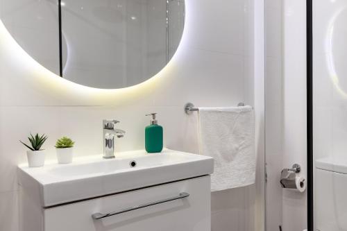 Baño blanco con lavabo y espejo en Precioso apartamento cerca de Bilbao Exhibition Center -BEC-, Bilbao y playas, en Barakaldo