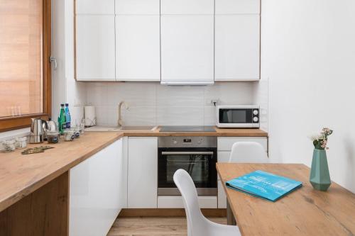 eine Küche mit weißen Schränken und einer hölzernen Arbeitsplatte in der Unterkunft Rent like home - Grzybowska 85 II in Warschau