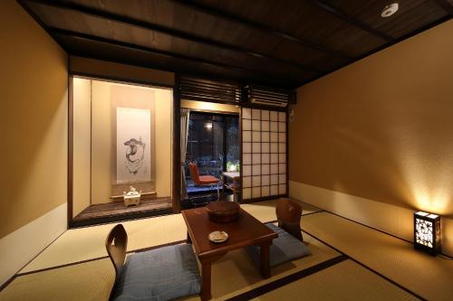 a room with a table and chairs and a window at Matsubaya Ryokan in Kyoto