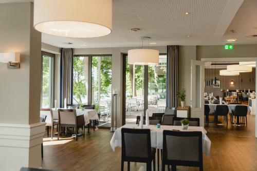 a restaurant with white tables and chairs and windows at ConventGarten Hotel & Restaurant - am Nord-Ostsee-Kanal in Rendsburg