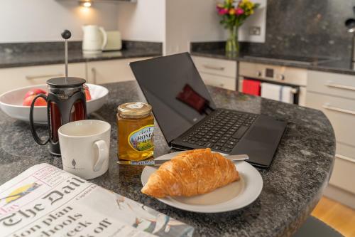 a laptop computer sitting on a kitchen counter with a plate of bread at Castle Properties:Eton-The College in Windsor